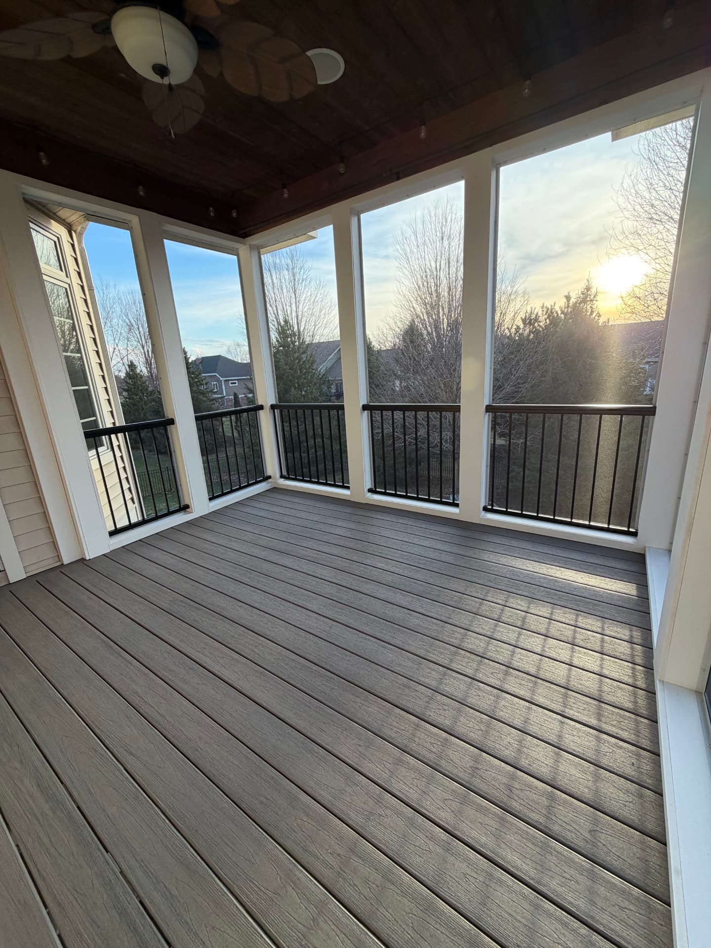 Screened three-season porch interior with dark composite flooring and black railings